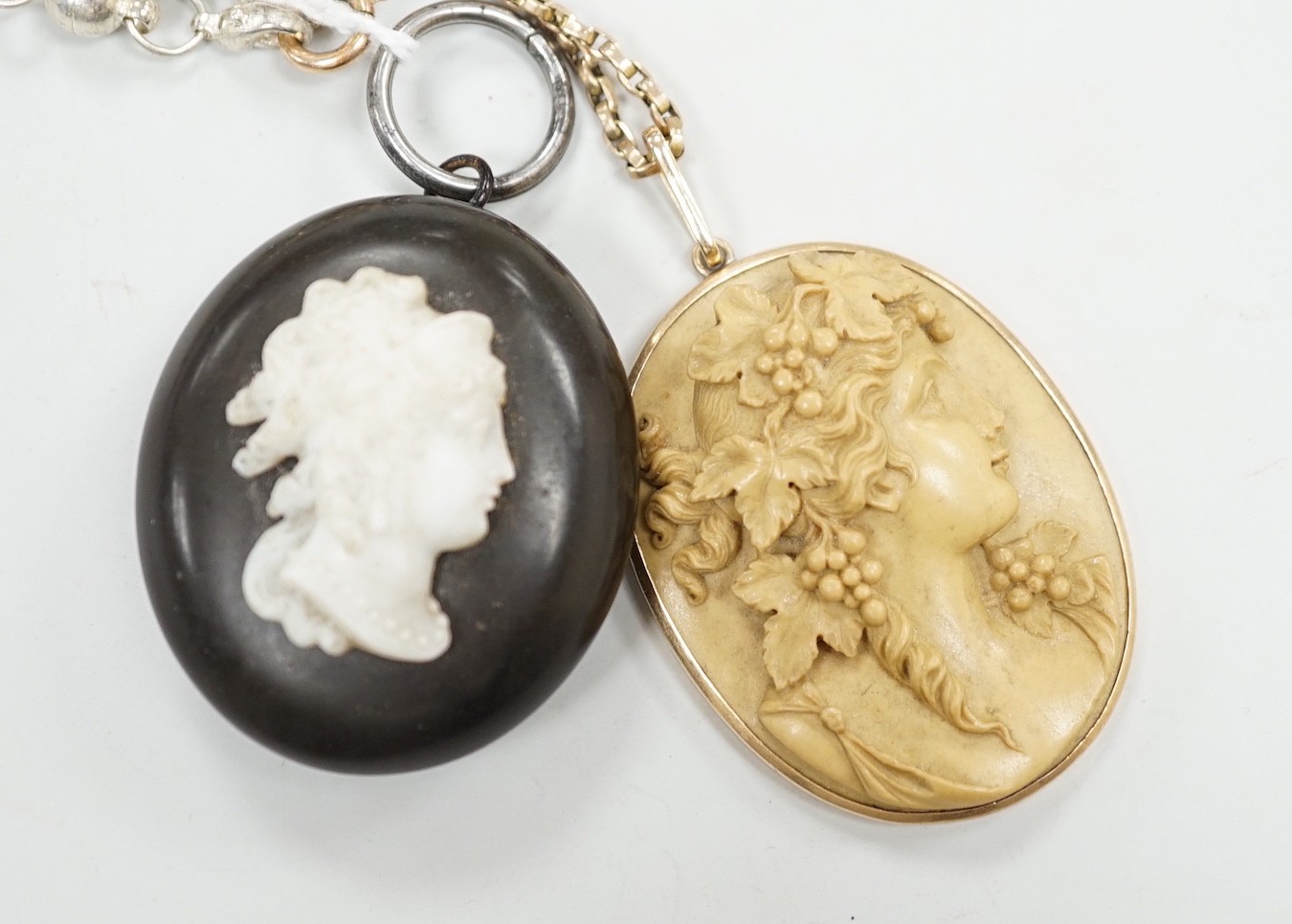 A late Victorian yellow metal mounted oval lava pendant, carved with the bust of a lady to sinister, 47mm, on a 9ct chain, together with phenolic oval locket.